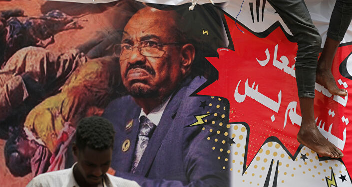 Sudan'da bir gösterici devrik lider Ömer Beşir'in posterinin önünde duruyor